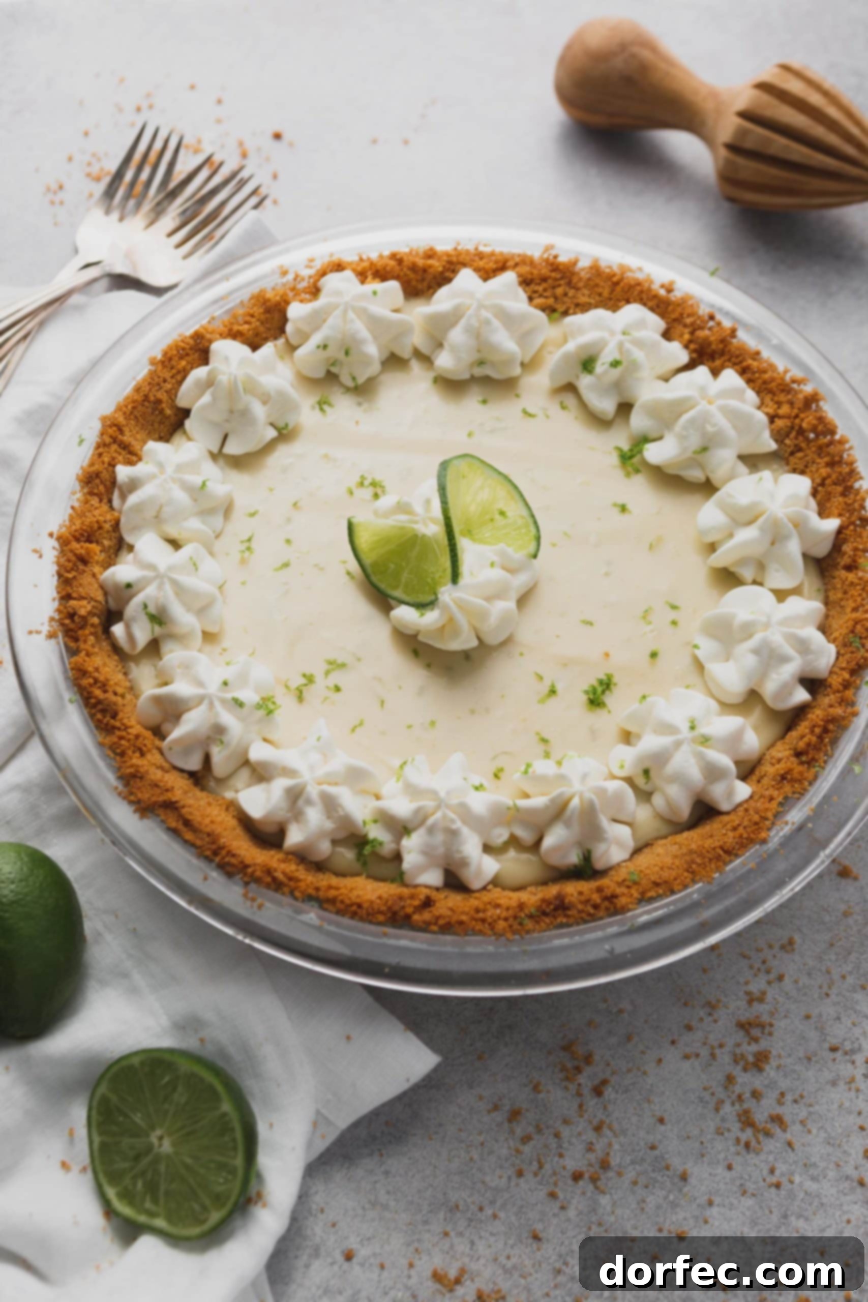 Best Key Lime Pie Recipe A vibrant key lime pie in a golden graham cracker crust, elegantly decorated with swirls of whipped cream and thin slices of fresh lime.