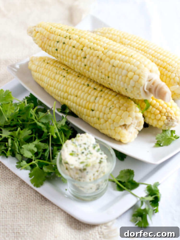 Fresh steamed corn on the cob, generously coated with a vibrant cilantro butter.