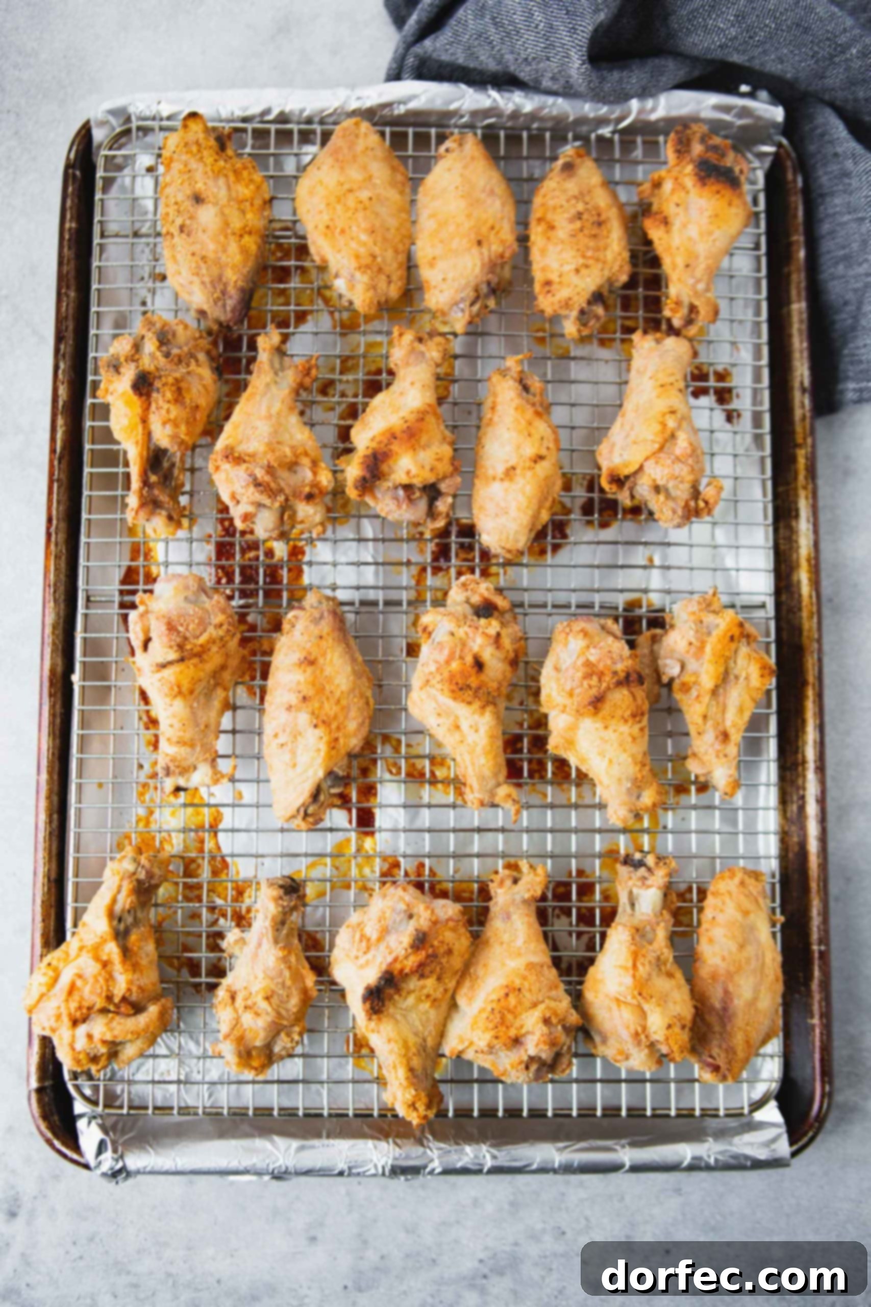 Air Fryer Teriyaki Chicken Wings a photo of golden baked chicken wings on a wire rack in a baking sheet.