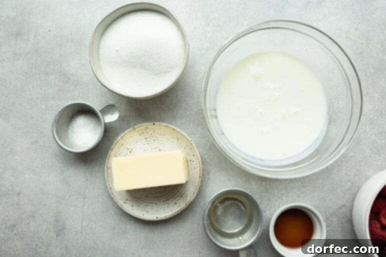 Irresistible Buttermilk Syrup 3 All 6 essential ingredients for homemade buttermilk syrup laid out: a stick of butter, white granulated sugar, a measuring cup of buttermilk, a bottle of vanilla extract, a small bowl of corn syrup, and a spoon of baking soda.
