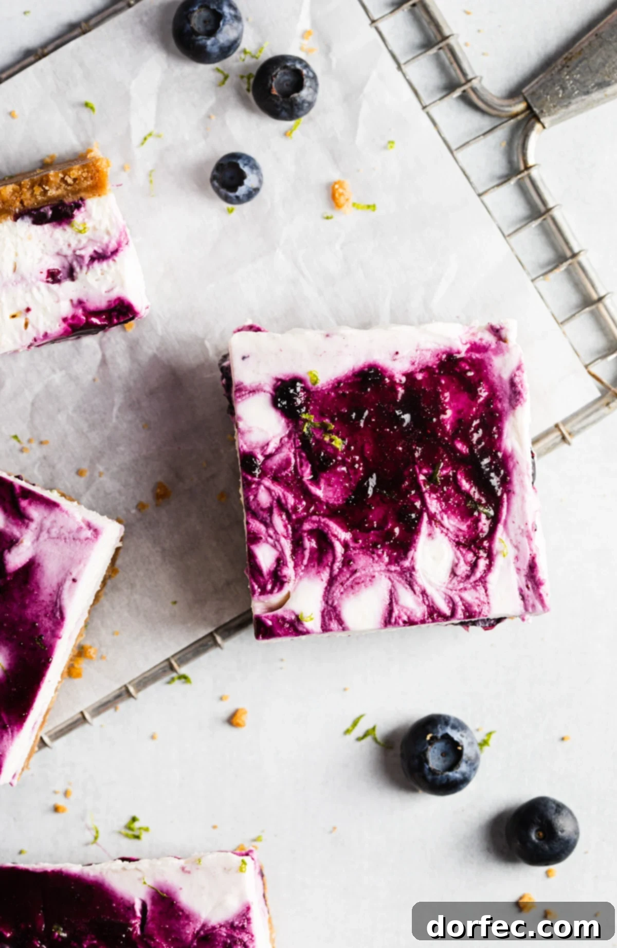 Three No-Bake Blueberry Lime Cheesecake Bars on a serving plate, ready to be enjoyed