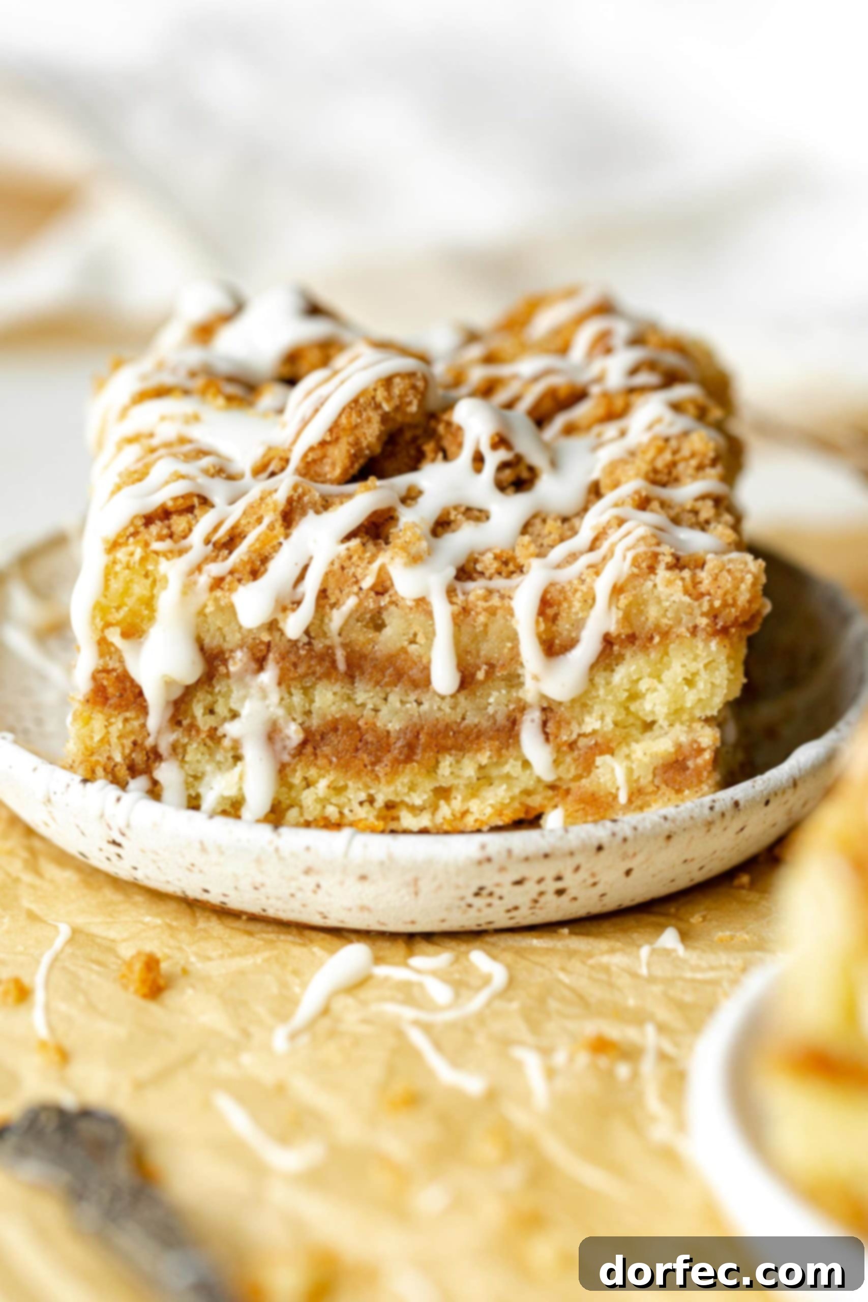 a photo of a single piece of coffee cake on a small saucer topped with a drizzle of icing.