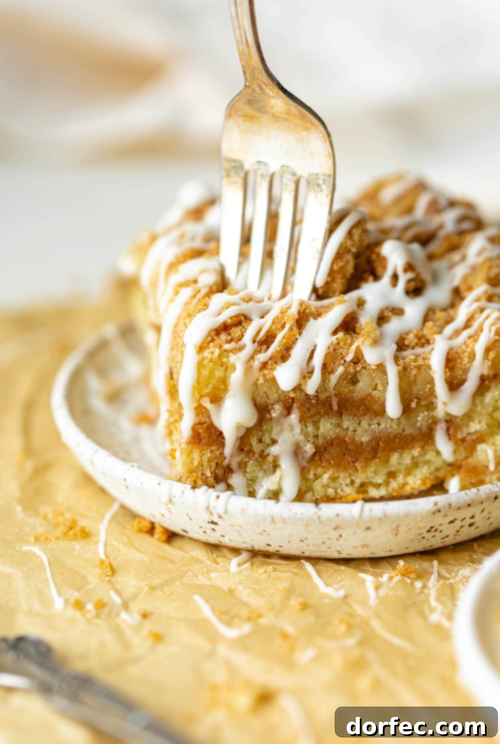 a photo of a fork being stuck into the corner of a piece of coffee cake.