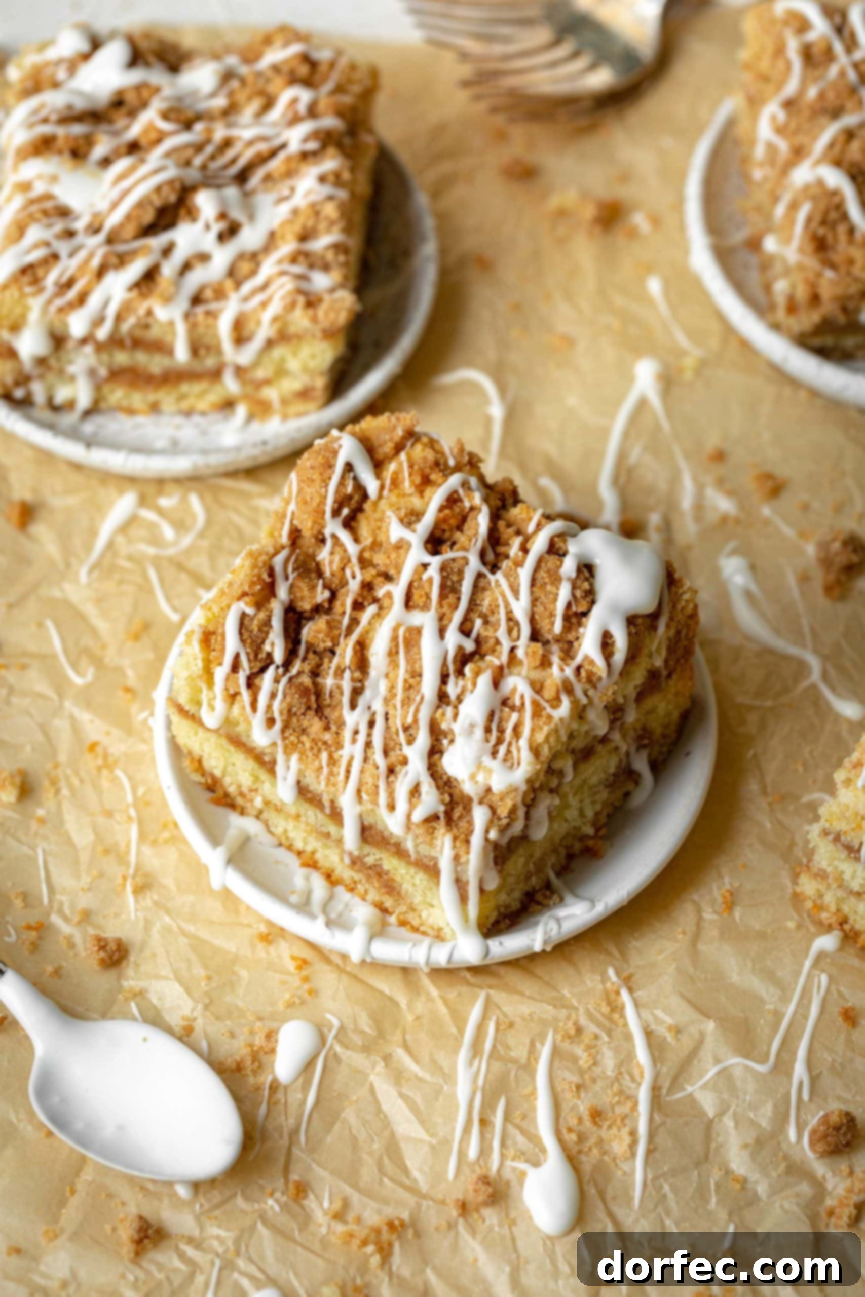 a photo of a piece of coffee cake sitting on a small saucer and the piece has been drizzled with icing.