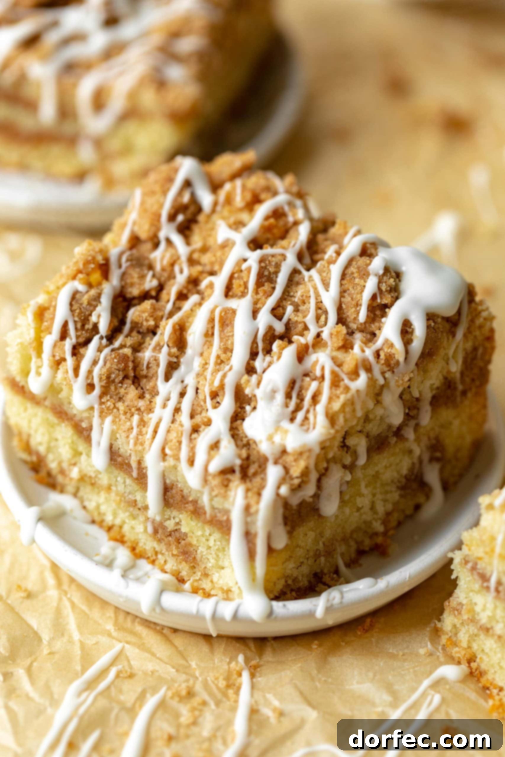 a photo of a piece of coffee cake topped with a cinnamon streusel and drizzles of icing.