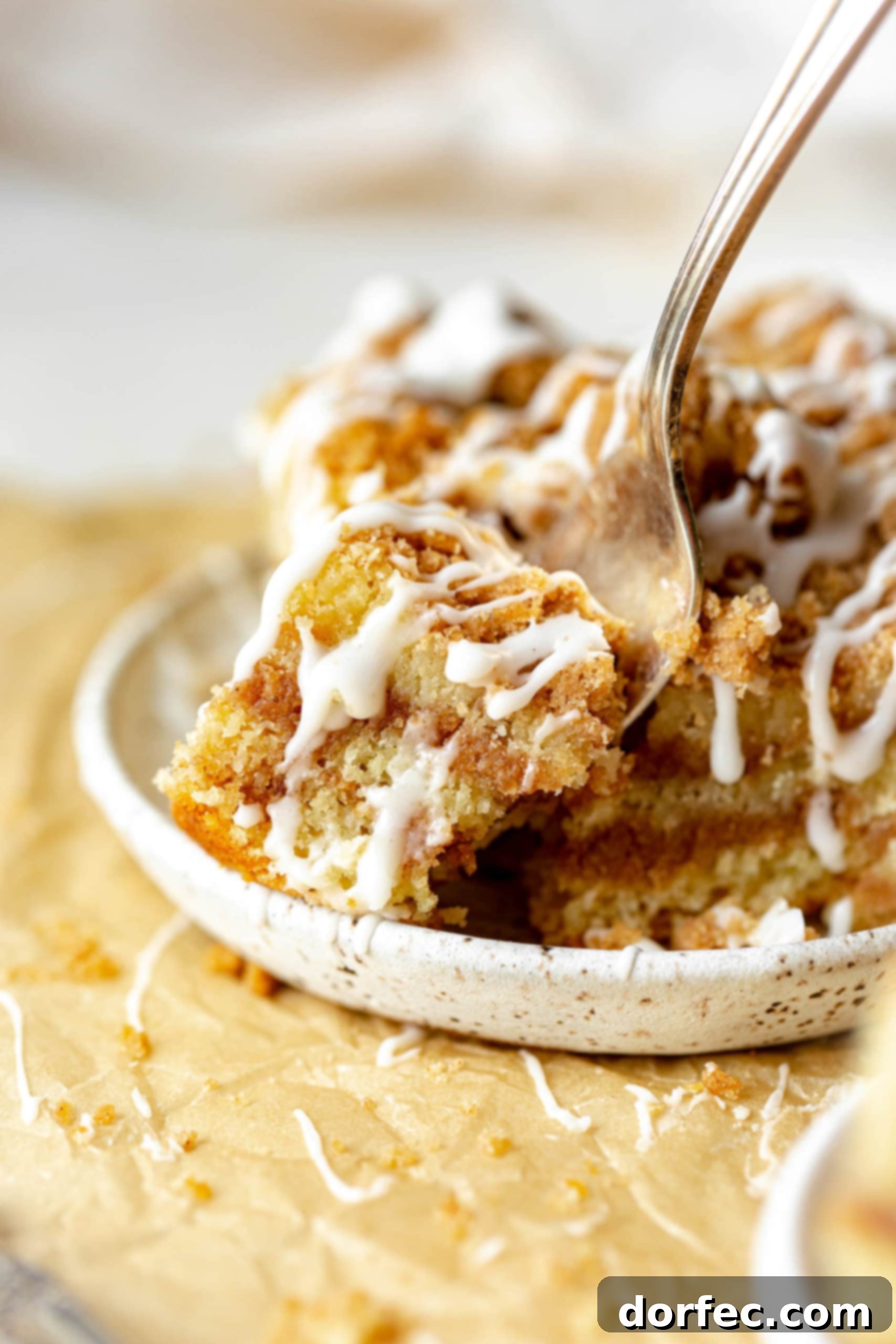 a photo of a fork removing a bite from the corner of a piece of moist perfect coffee cake.