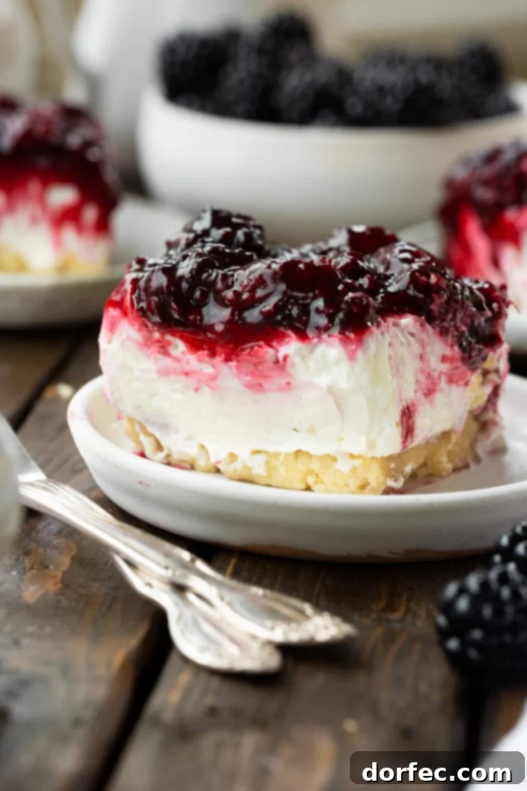 A beautifully presented cheesecake bar featuring a golden pie crust base, a thick layer of creamy white cheesecake, and a vibrant mixed berry topping.