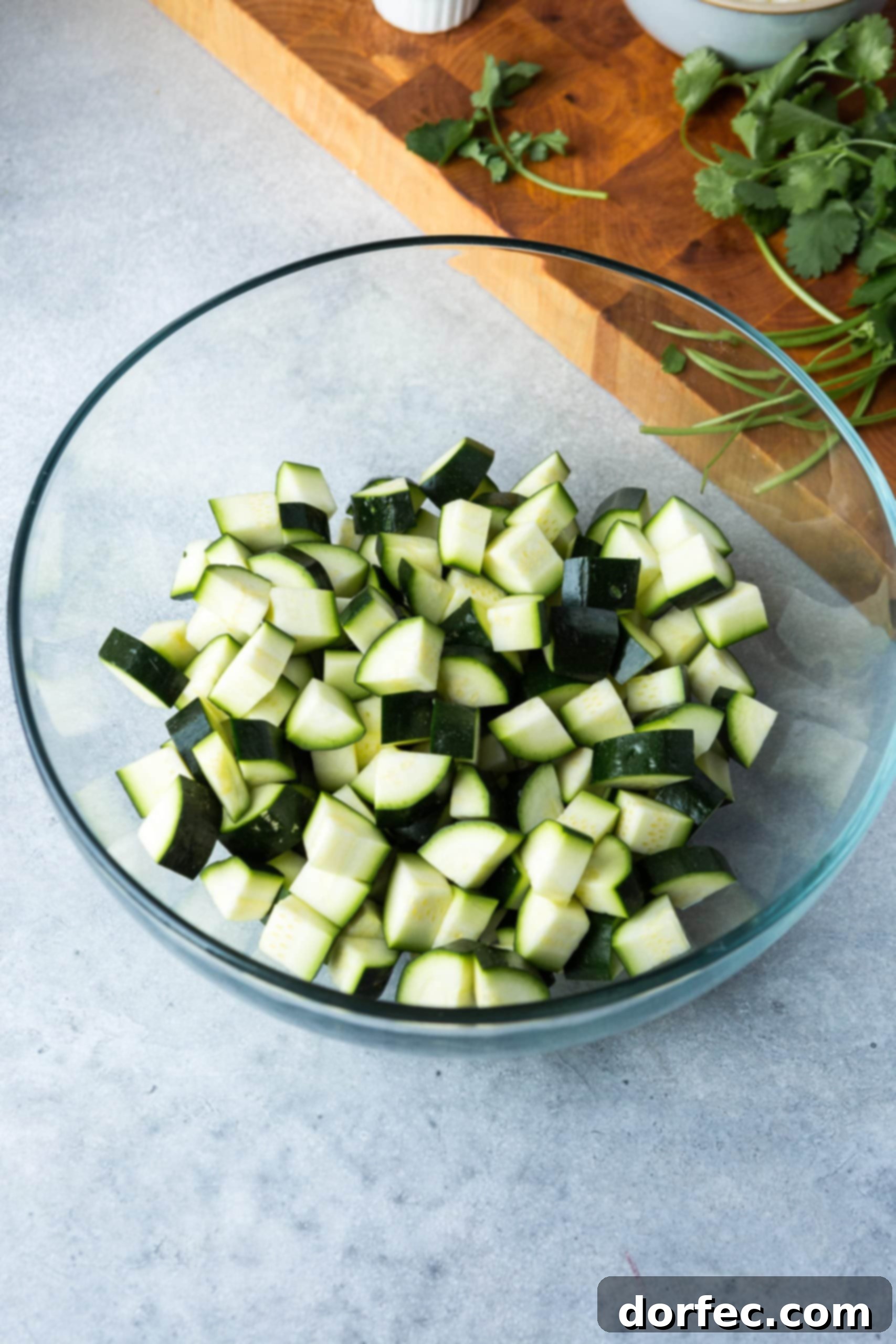 Bite-sized chunks of fresh zucchini in a large glass mixing bowl, perfectly chopped and ready for seasoning.
