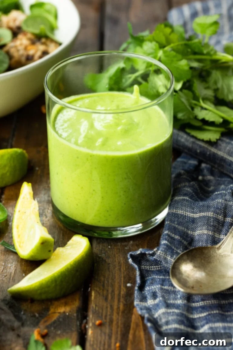 A close-up shot of a glass cup filled with bright green avocado cilantro lime dressing, showcasing its creamy texture.