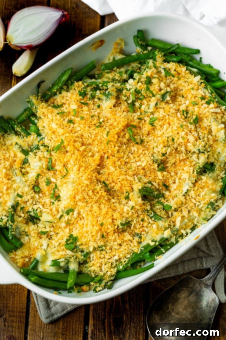 A photo of a white casserole dish filled with creamy green beans topped with a golden panko breadcrumb topping, freshly baked.