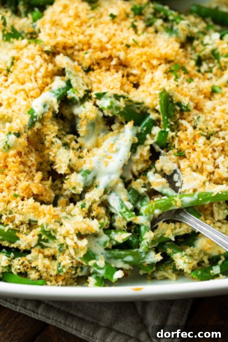 A close-up photo of green beans mixed with a creamy ranch sauce, all topped with a golden crunchy panko topping, ready to be scooped.
