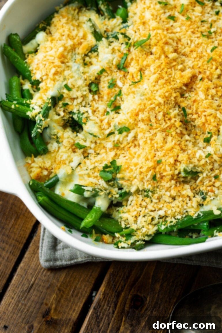 A photo of the corner of a casserole dish filled with green beans, creamy ranch sauce, and a crunchy golden panko topping.