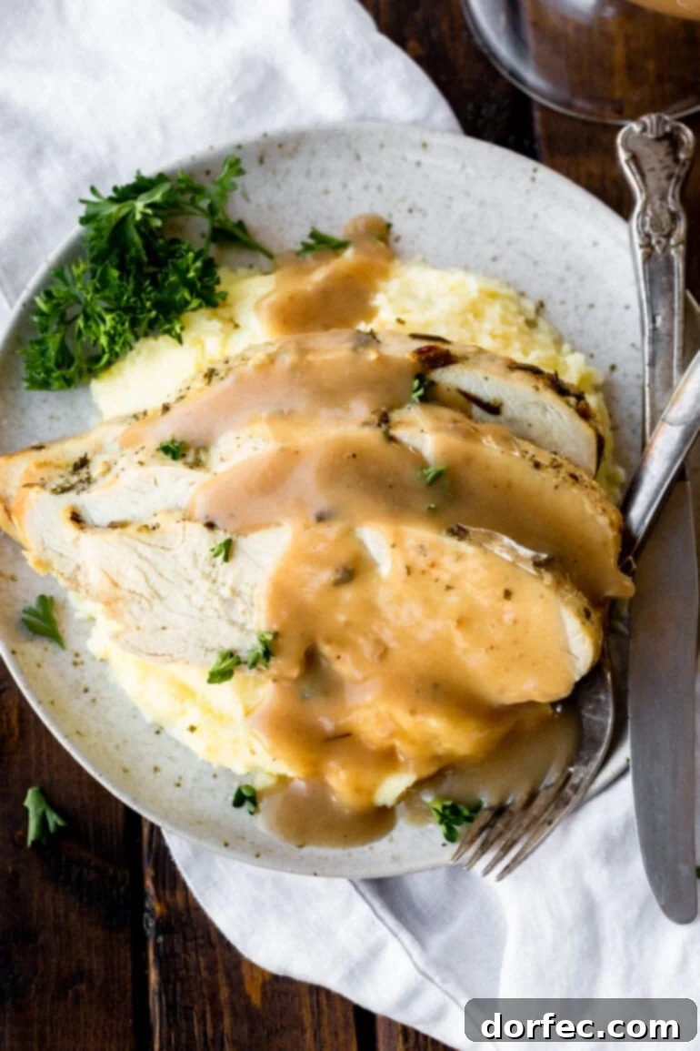 A photo of homemade turkey gravy generously poured over creamy mashed potatoes, garnished with fresh herbs.