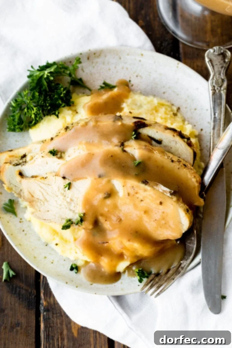 A photo taken from above of a dinner plate abundantly filled with fluffy mashed potatoes, drenched in creamy homemade turkey gravy, ready to be enjoyed.