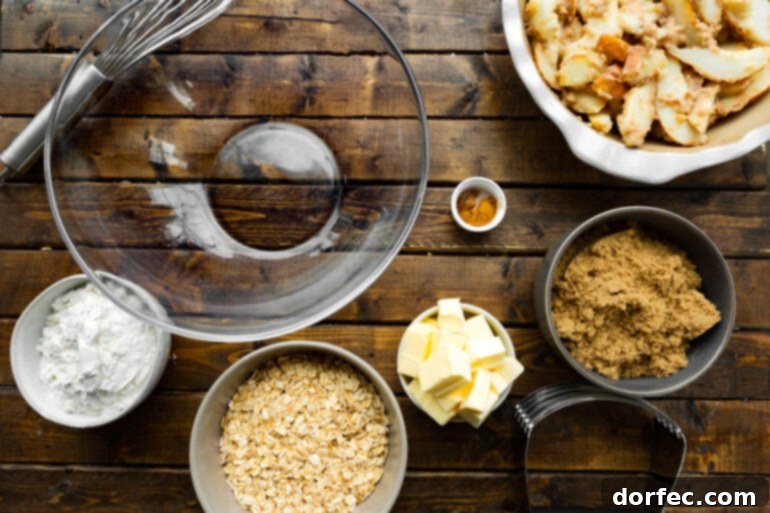A flat lay photo displaying all the individual ingredients for a pear crisp recipe in separate bowls, including oats, butter, cinnamon, brown sugar, and sliced pears.