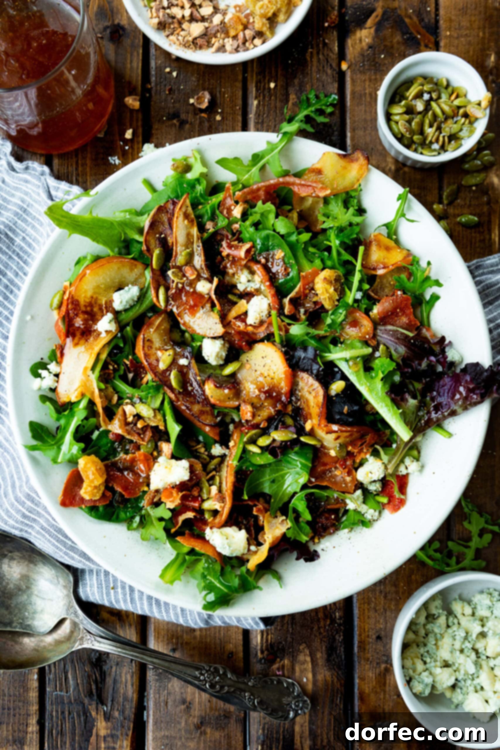 Autumn Harvest Roasted Apple & Pear Salad An overhead shot of a large white plate overflowing with a vibrant mixed greens salad, generously topped with an abundance of perfectly roasted apples and pears, showcasing the salad's fresh and inviting presentation.