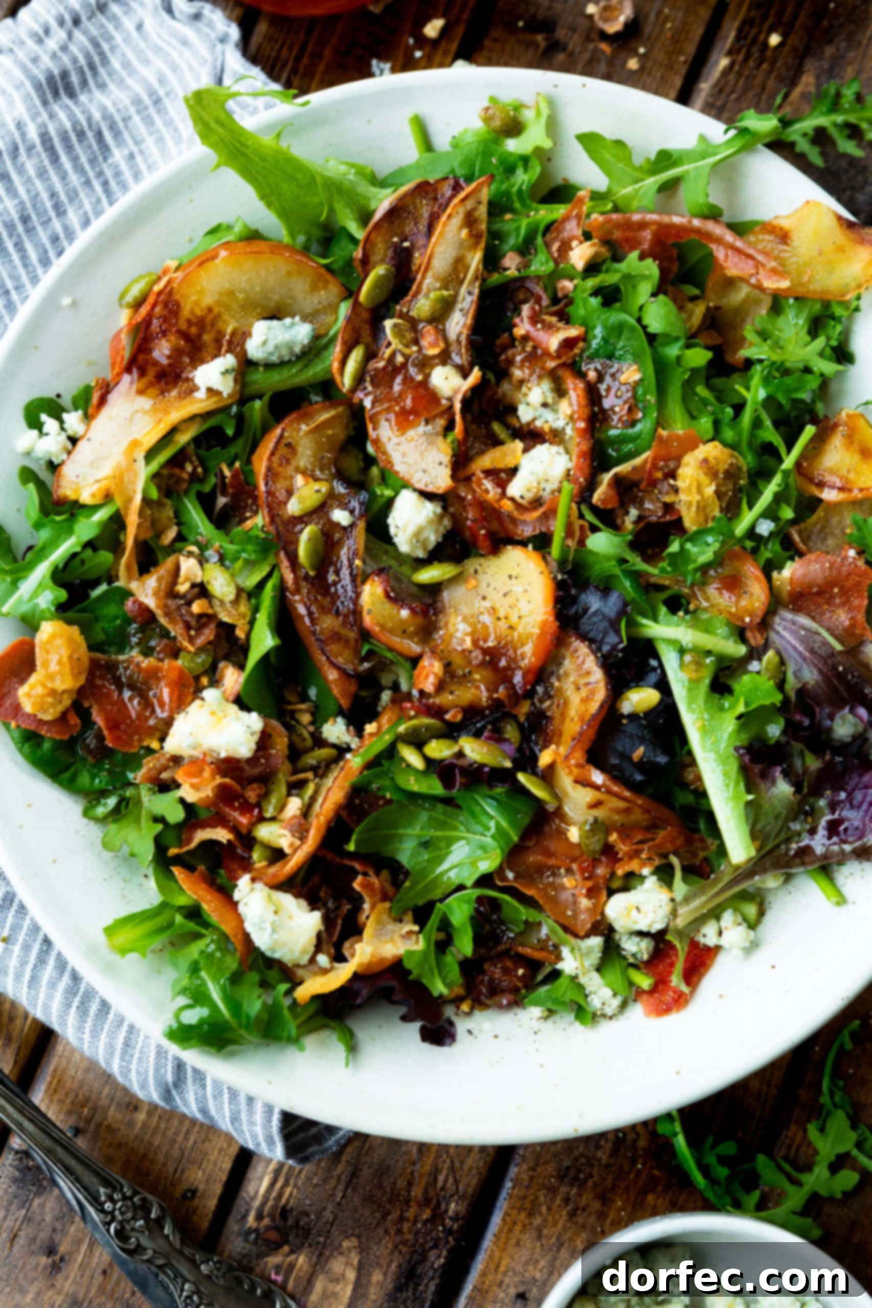 Delectable Roasted Pear & Apple Salad with Vinaigrette A large, beautifully arranged plate of roasted pear and apple salad, generously topped with a homemade caramelized shallot maple vinaigrette, ready to be served and enjoyed.