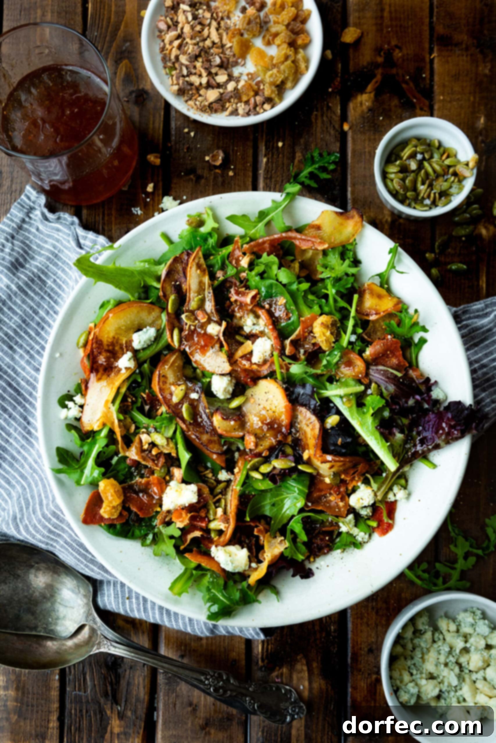 Signature Roasted Pear & Apple Salad with Vinaigrette An inviting overhead photograph capturing a roasted pear and apple salad, beautifully presented over a bed of mixed greens and generously drizzled with a homemade caramelized shallot maple vinaigrette, ready for enjoyment.