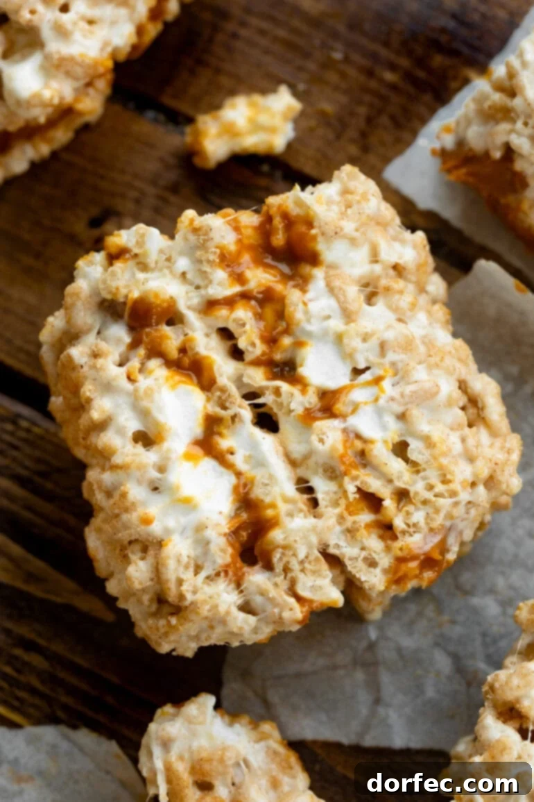 a photo of a two gooey rice crispy treats that have been stuffed with dulce de leche standing on end so you can see the cross sections of the treats.