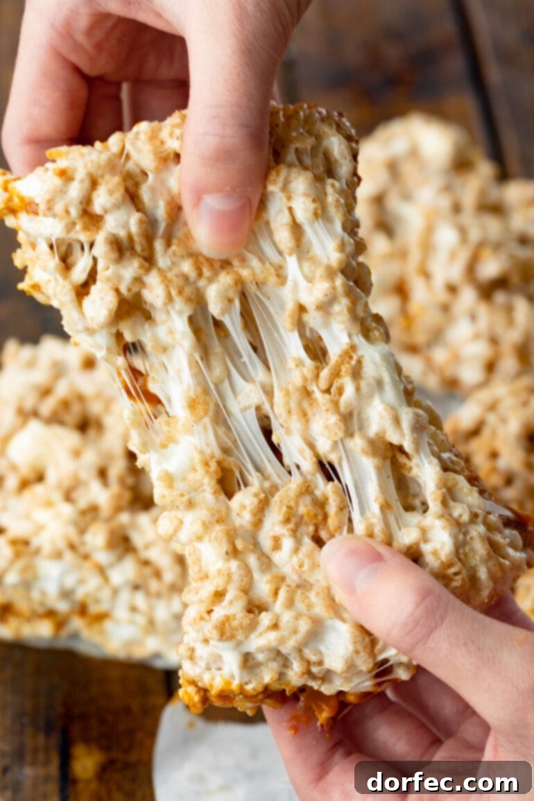a photo of someone pulling apart a gooey dulce de leche rice krispie treat with the marshmallow stretching between halves.