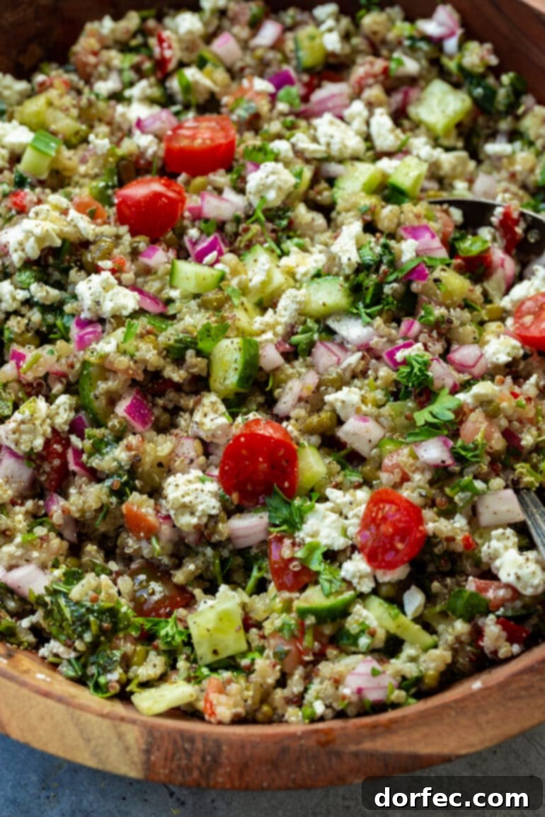 a photo of a Med quinoa bowl including cucumbers, tomatoes, feta, red onions, fresh herbs and topped with a homemade dressing.
