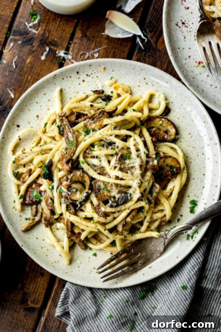 A close-up shot of a plate laden with a generous serving of creamy mushroom pasta, with a fork poised invitingly beside it, inviting the viewer to indulge.