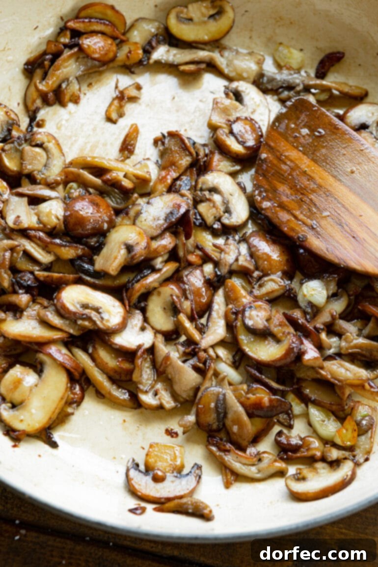A close-up photograph of beautifully sliced, sautéed, and caramelized mushrooms, golden-brown and glistening, ready to be incorporated into a dish.