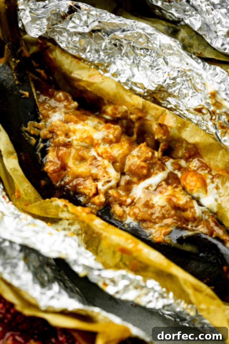 Our Favorite Campfire Banana Boats 14 Two savory campfire banana boats, expertly roasted and generously drizzled with rich caramel sauce, highlighting their golden-brown perfection.