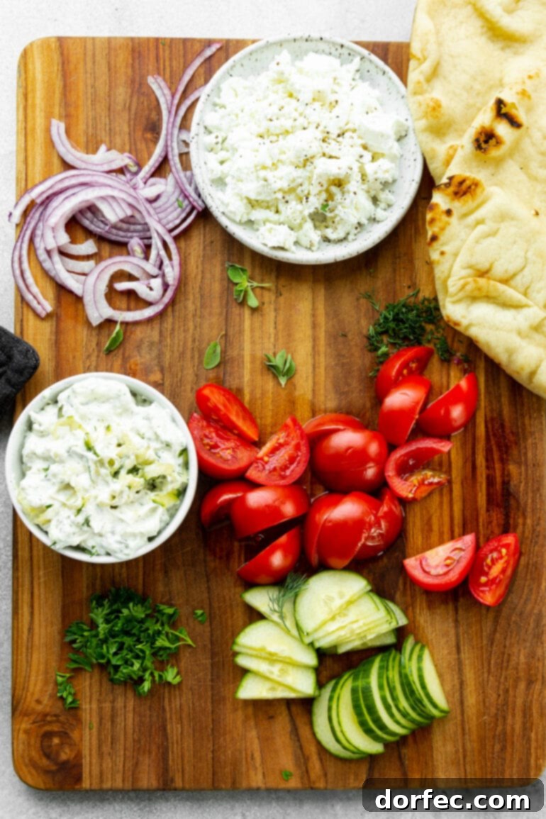 Cade's Signature Chicken Gyros 4 A photo of all the fresh and flavorful toppings that go on a gyro - sliced tomatoes, cucumber, fresh parsley, sliced red onions, feta, and tzatziki sauce.