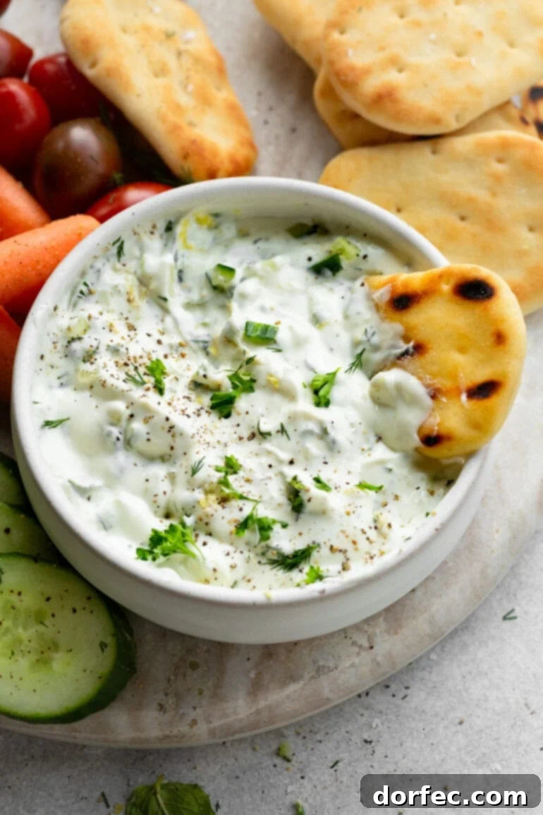 Creamy homemade tzatziki dip served with warm pita bread, highlighting its rich texture.