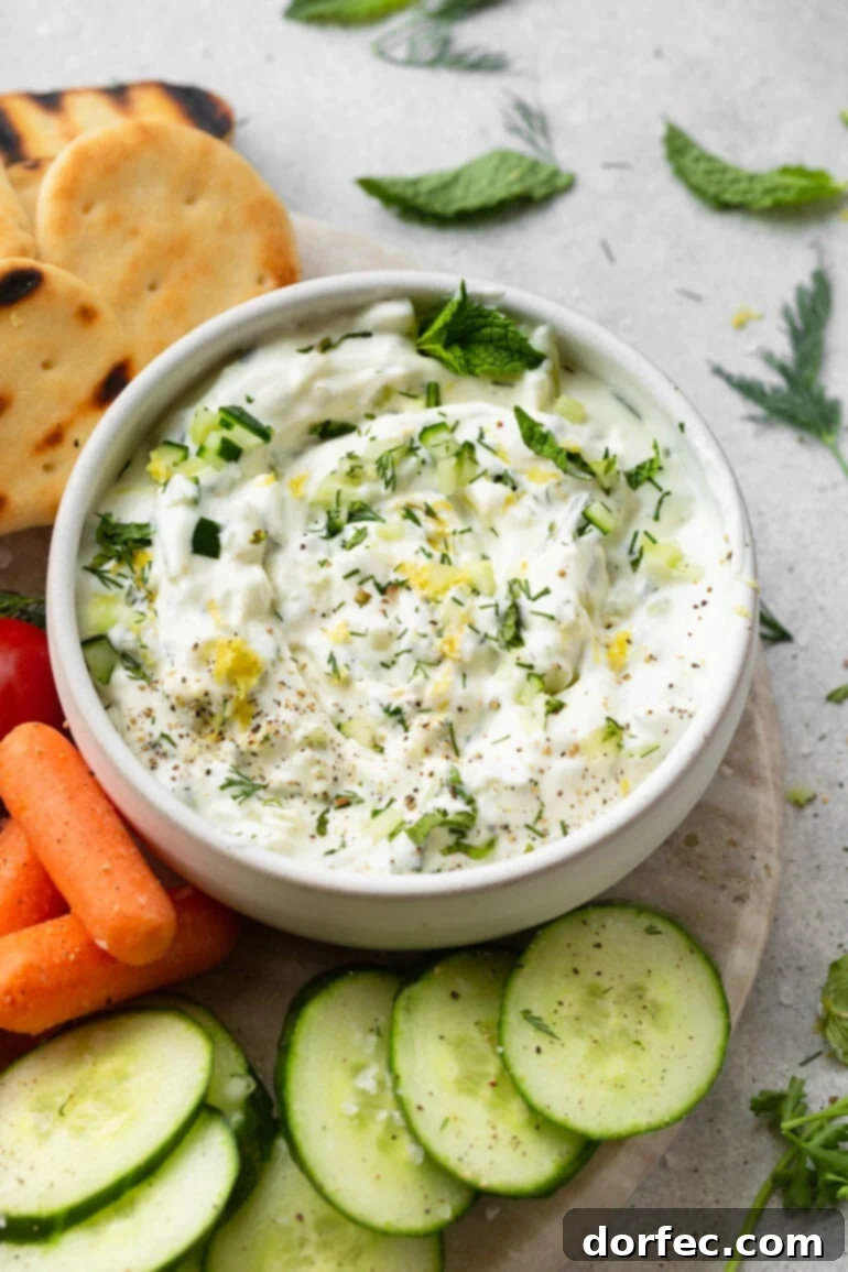 Vibrant tzatziki dip surrounded by colorful fresh vegetables and pita wedges, perfect for sharing.