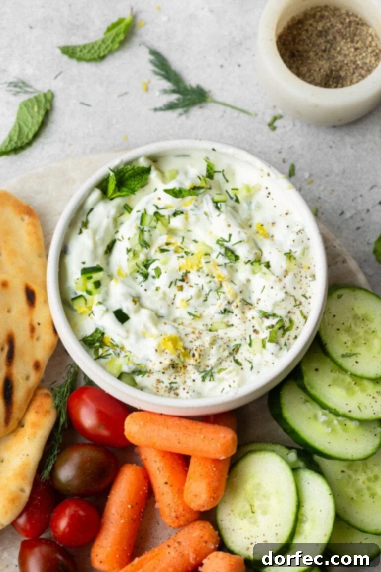 Delicious homemade tzatziki served with a medley of fresh crudités and naan bread, perfect for a healthy snack.