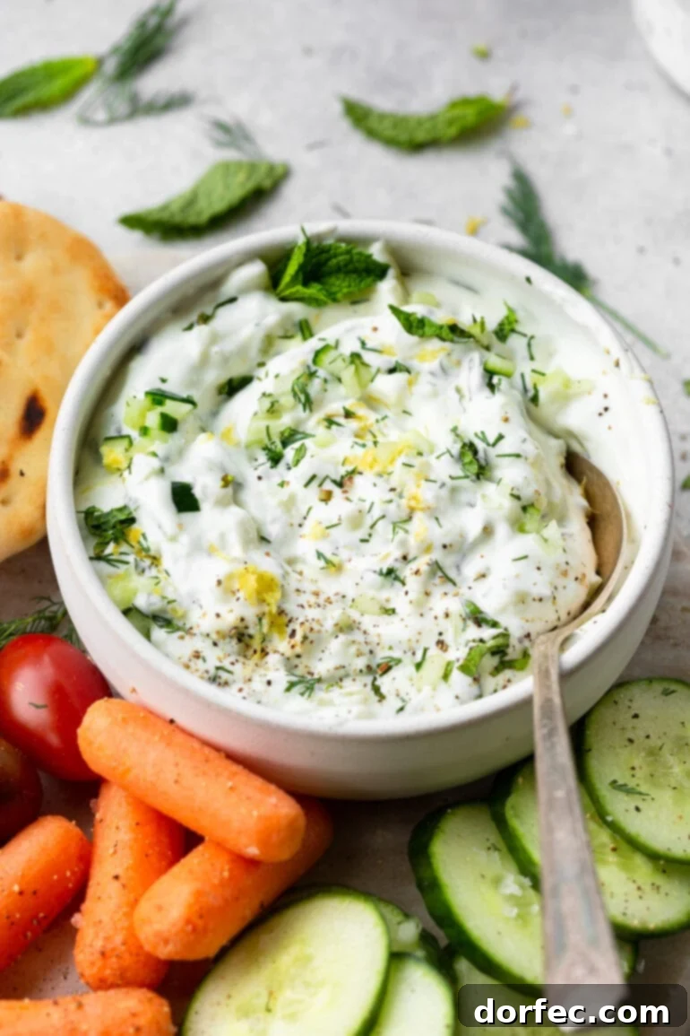 Close-up of a rich and creamy homemade tzatziki sauce, garnished with fresh dill and cracked black pepper, ready for serving.