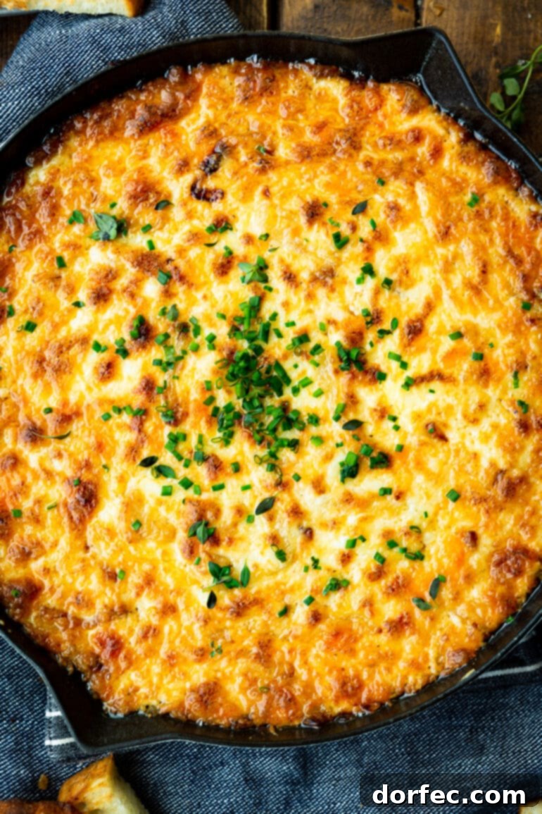A large cast iron skillet filled with golden baked hot caramelized onion cheese dip, ready to be served.