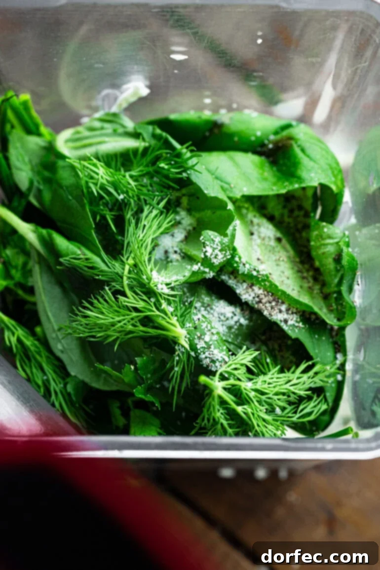 A close-up, top-down view of a blender filled with all the fresh ingredients for creamy basil dressing, ready to be blended into a smooth concoction.