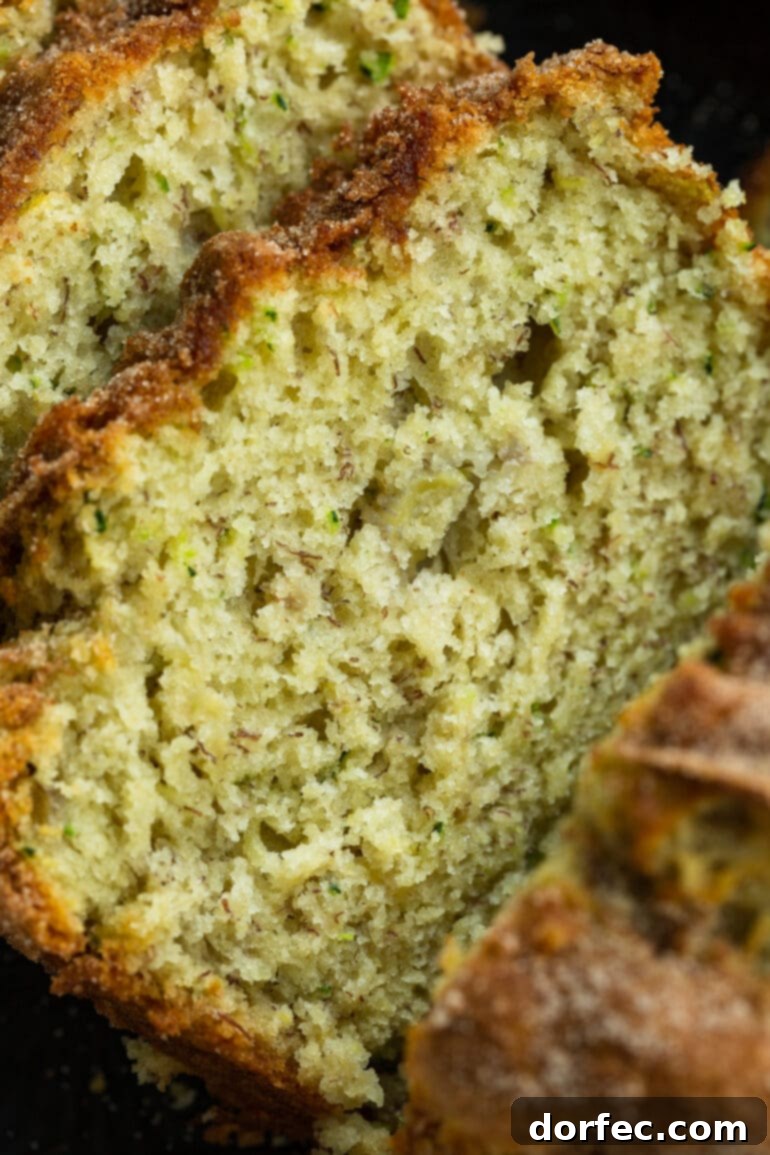 A close-up photo of a single, perfectly sliced piece of banana zucchini bread, revealing its moist interior and the golden cinnamon sugar topping.
