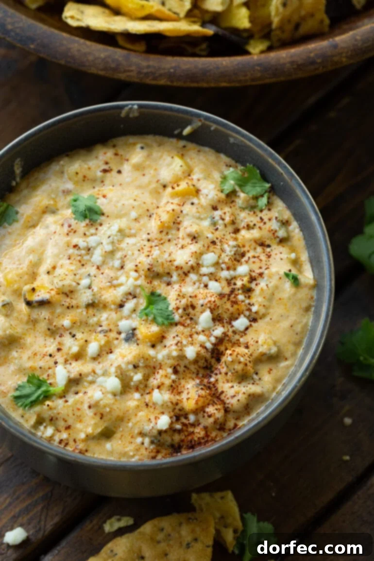 A large bowl of creamy Mexican street corn dip, garnished with fresh cilantro and a sprinkle of chili powder, ready to serve at a party.