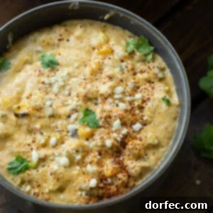 A top-down view of a small square bowl filled with Mexican street corn dip, garnished with fresh herbs and spices.