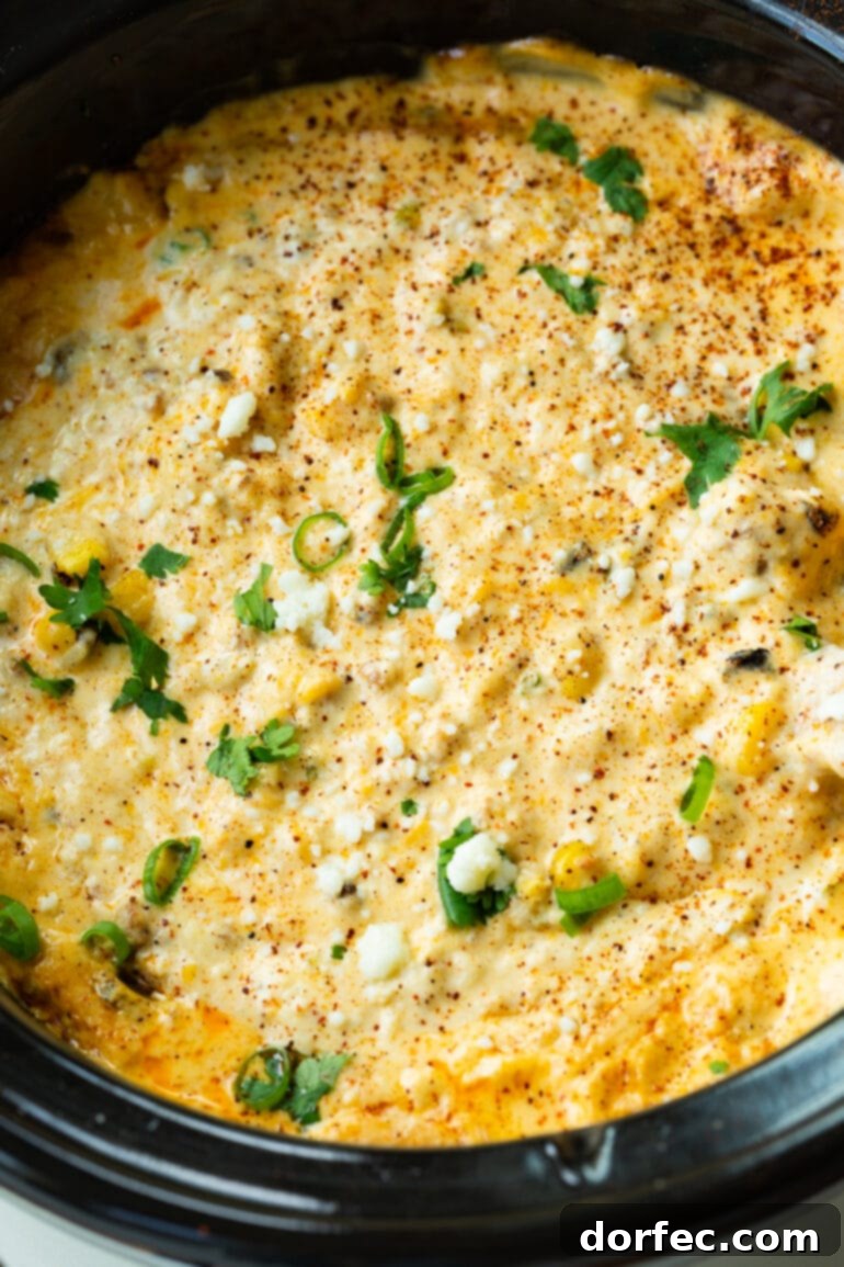 A close-up photograph of steaming, hot, and creamy Mexican street corn dip, highlighting its inviting texture and rich colors.