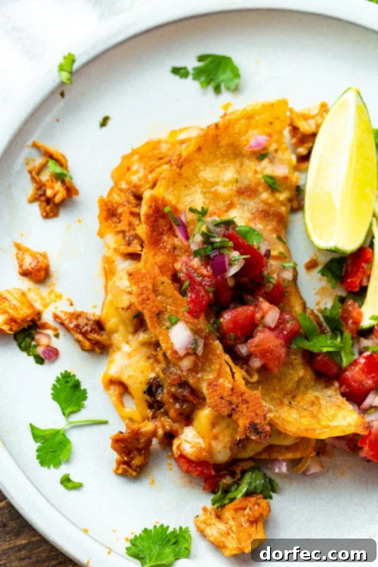 A close-up photo of a chicken birria taco featuring a perfectly crispy, golden-brown cheesy corn tortilla shell, topped with fresh pico de gallo.