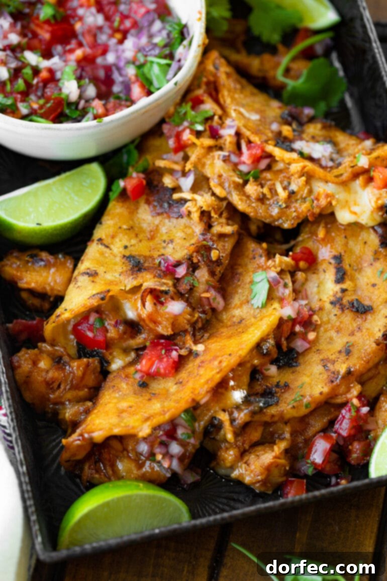 A photo of a tempting pile of crispy chicken birria tacos, generously topped with fresh pico de gallo, ready to be devoured.
