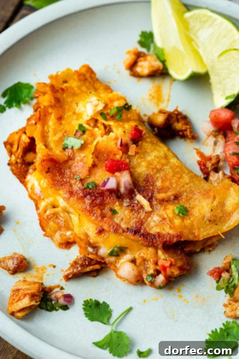 A close-up photo of a golden, crispy chicken birria taco with succulent melted cheese oozing out from the sides, highlighting its irresistible appeal.