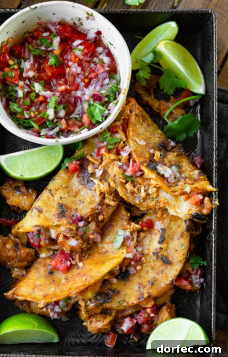 A stunning photo of a pile of crispy birria chicken tacos stacked artfully on a metal serving tray, accompanied by a small bowl of vibrant fresh pico de gallo on the side.