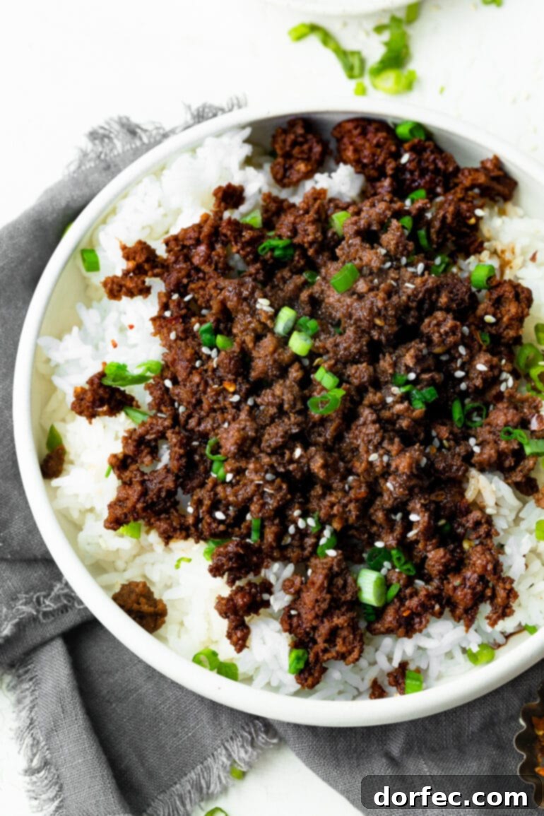 A photo of a bowl of Korean ground beef served over steamed white rice and topped with sliced green onions and sesame seeds, capturing its delicious appeal.