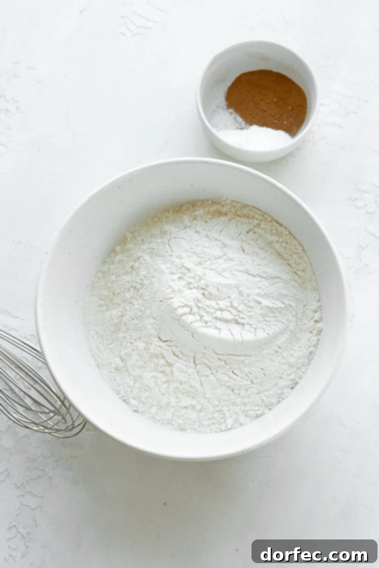 A close-up photograph of the dry ingredients for homemade apple bread, beautifully arranged in separate bowls, ready for mixing.