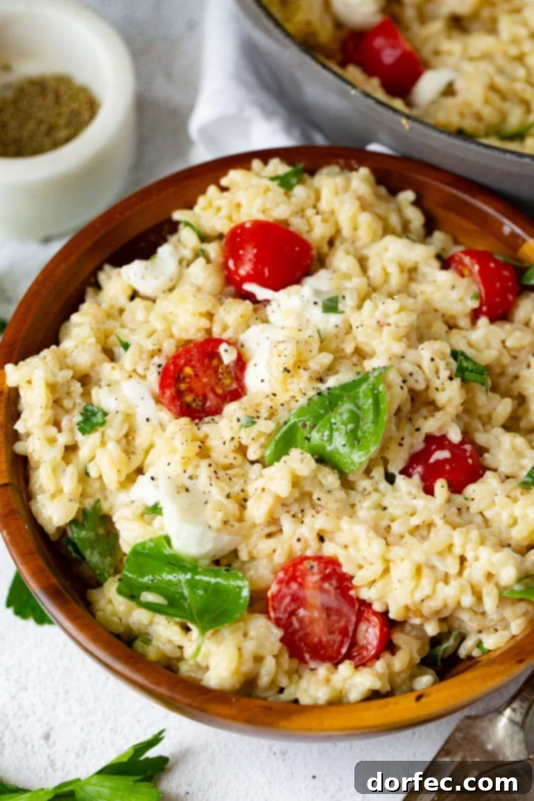 A fresh bowl of Caprese orzo salad with cherry tomatoes, mozzarella pearls, and fragrant basil leaves, ready for a light meal.