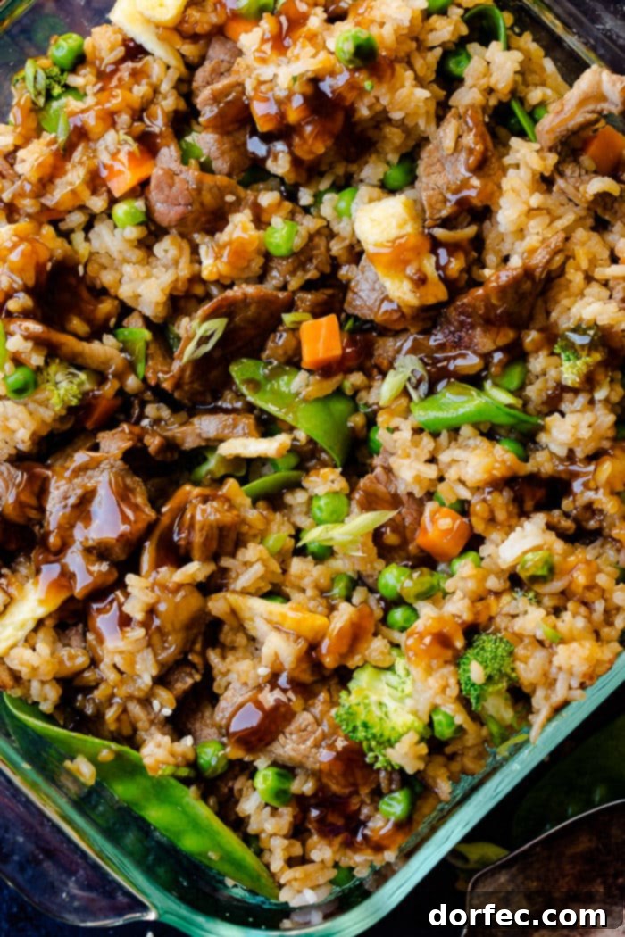 A savory Teriyaki Beef Casserole in a glass dish, filled with tender beef, fried rice, carrots, peas, broccoli, and snow peas.