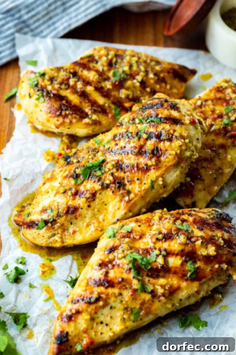 Your Weekly Meal Plan: September 18-24 4 Several perfectly golden-brown grilled chicken breasts, showcasing enticing diagonal grill marks and a visibly juicy, tender interior, artfully arranged on a rustic wooden serving board, ready to be sliced and served.