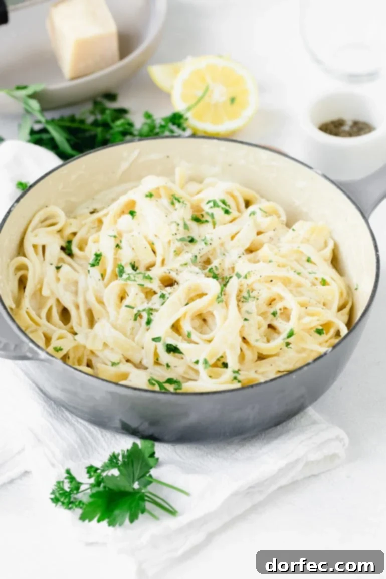 Your Weekly Meal Plan: September 18-24 9 A beautifully presented bowl of classic creamy fettuccine alfredo, generously sprinkled with vibrant fresh chopped parsley. Neatly arranged beside the bowl are fresh green parsley sprigs and bright yellow lemon wedges, adding a touch of freshness and contrast to the rich, decadent pasta dish.