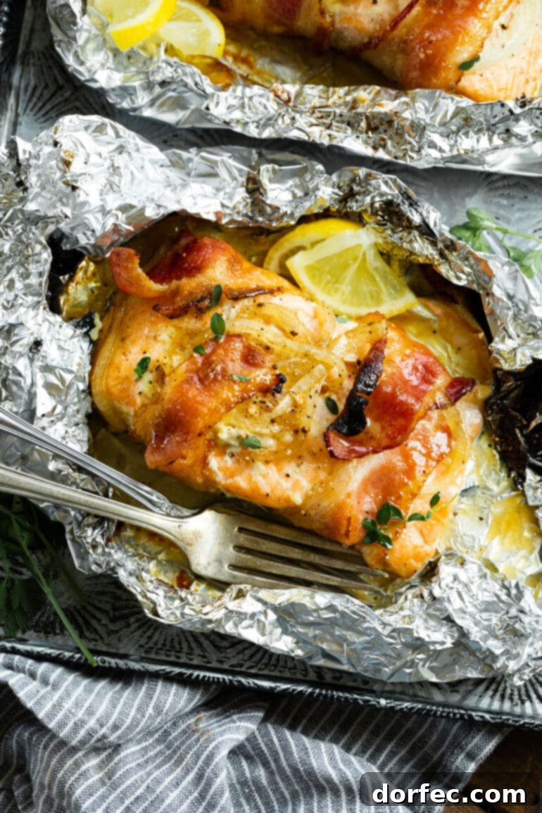 A delectable baked salmon fillet, cooked in foil and wrapped in crispy bacon, adorned with fresh herbs and bright lemon slices, presented on a wooden board.